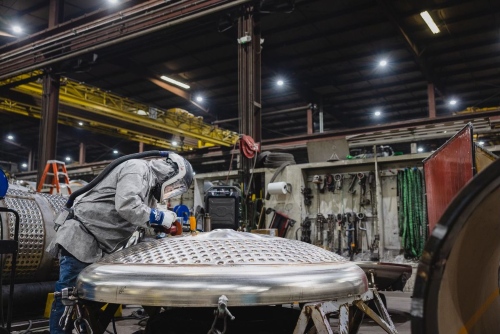 worker in protective suit working on a large metal component